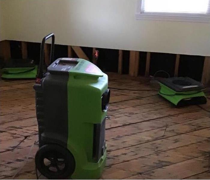 Drying equipment placed on damaged wood floors after flooding due to a storm