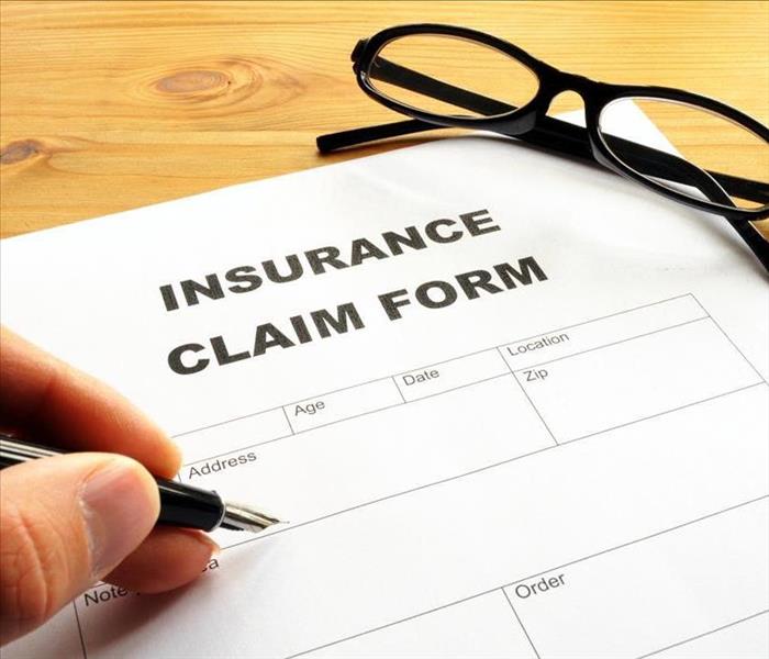 Image of an insurance claim form and a hand filling in the form.